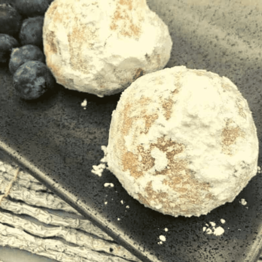 Golden air fryer blueberry pie bombs with oozing blueberry filling on a plate.