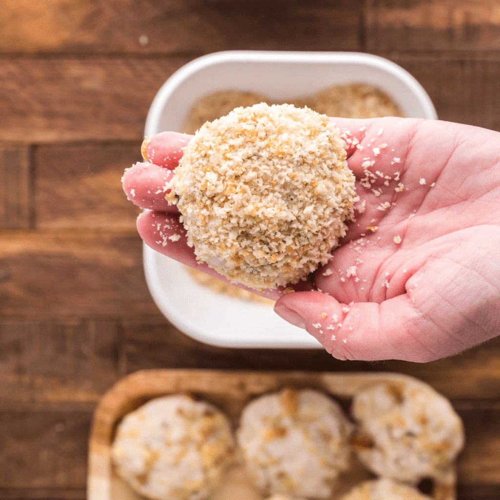 Making chicken croquettes, holding a prepared chicken croquette, in hand.