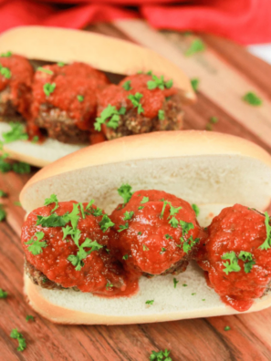 Golden brown air fryer chicken meatballs in a white bowl with marinara and fresh parsley