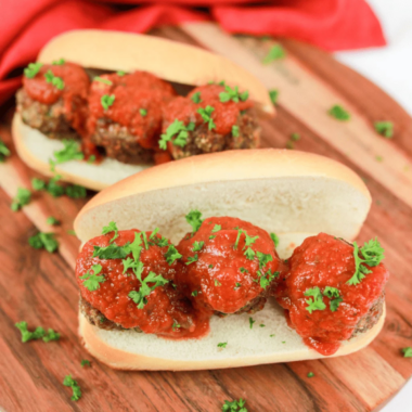 Golden brown air fryer chicken meatballs in a white bowl with marinara and fresh parsley