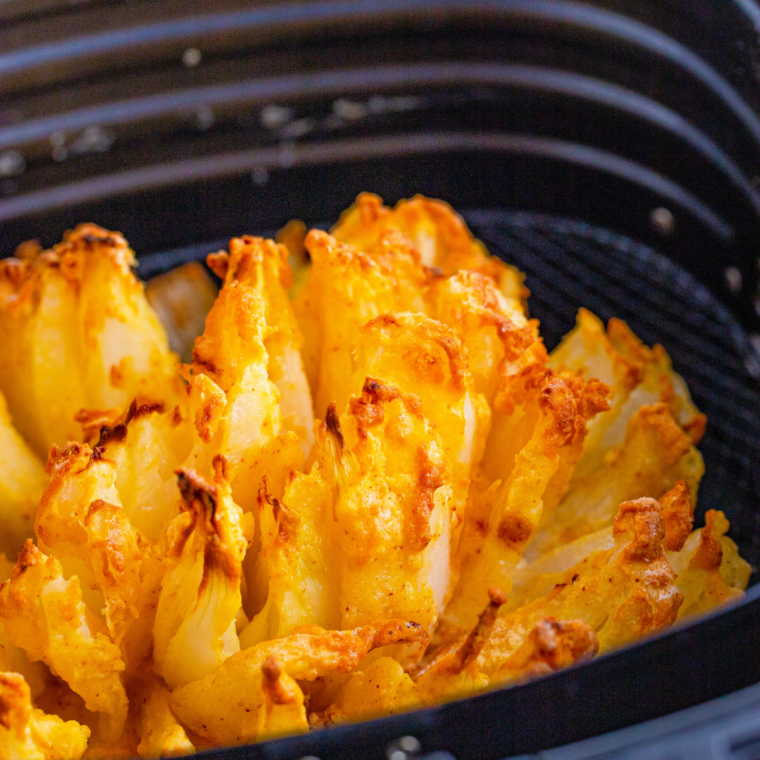 Golden, crispy bloomin' onion cooked in the air fryer basket, petals fanned open