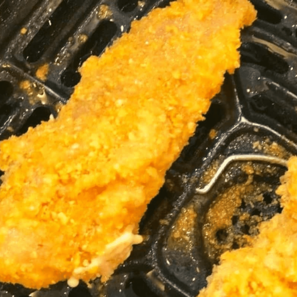 Cooked Cornflake Chicken Tenders in the air fryer basket.