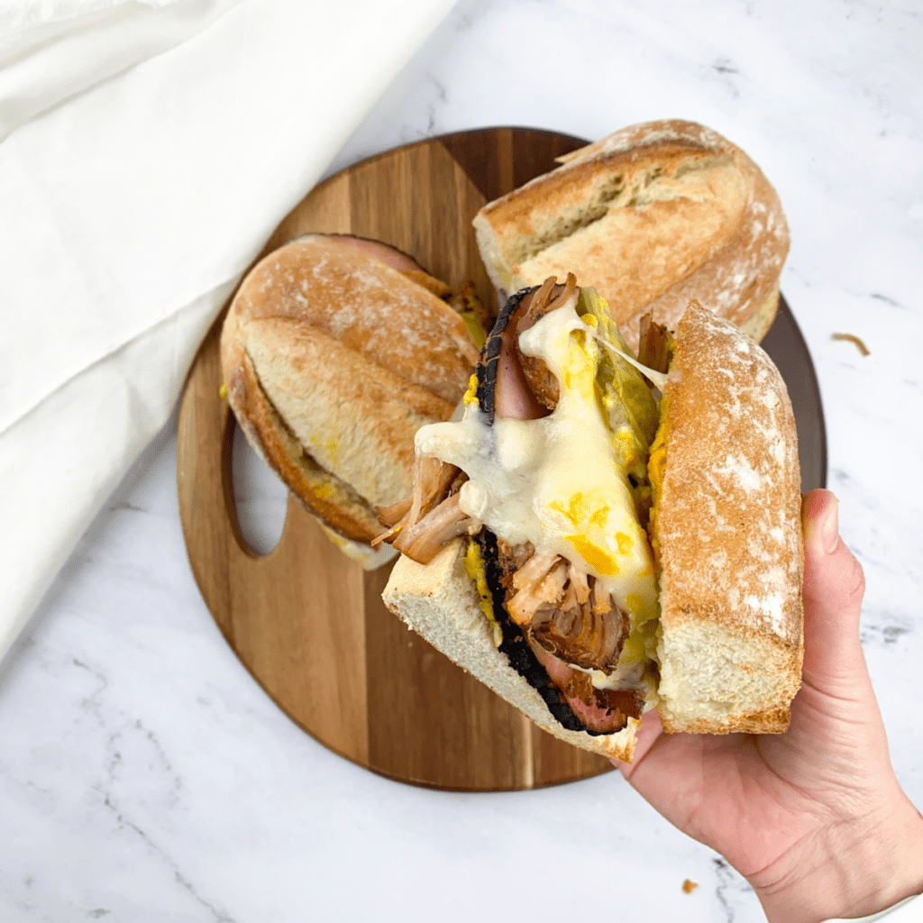 Air fryer cooking Cuban sandwich with crispy crust and melty cheese."