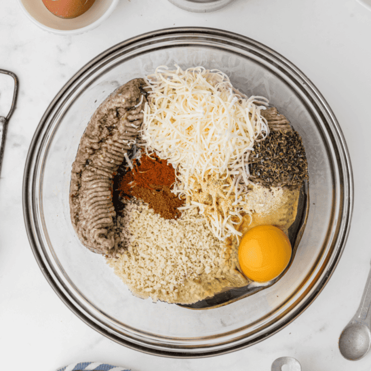 Mixing ground lamb with spices and herbs in a large bowl for lamb meatballs