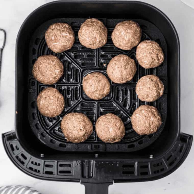 Lamb meatballs arranged in a single layer in the air fryer basket, ready to cook.