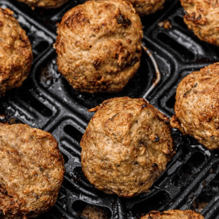Golden-brown lamb meatballs freshly cooked in the air fryer basket.