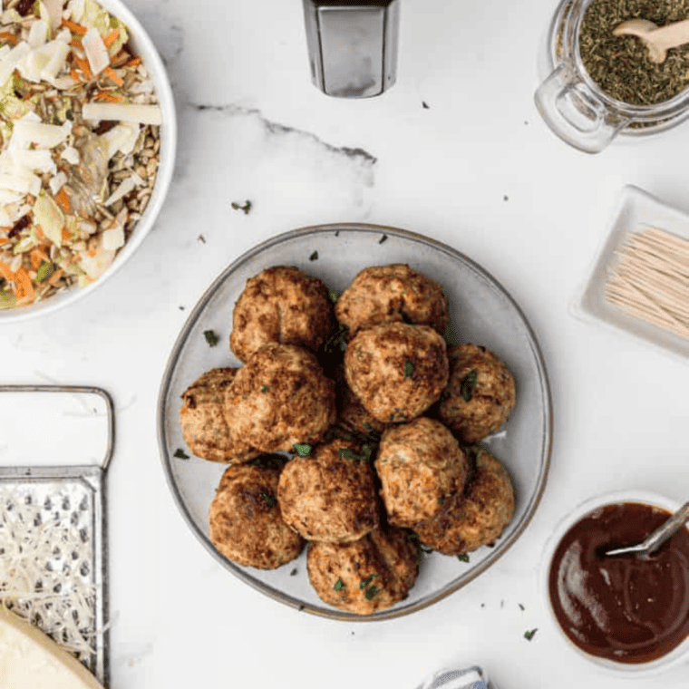 "Savory air fryer lamb meatballs served with dipping sauce on a white plate."