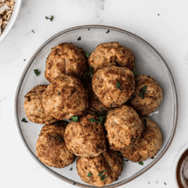 Air fryer lamb meatballs garnished with lemon wedges and fresh herbs.