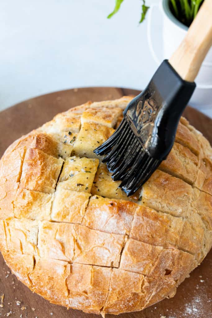 Mixing garlic butter with melted butter, garlic, parsley, and onion powder, then brushing it onto the bread and adding shredded cheese into the cracks.