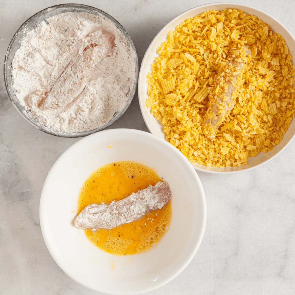 Coating chicken in flour, egg, and crushed potato chips before placing in a single layer in the air fryer basket