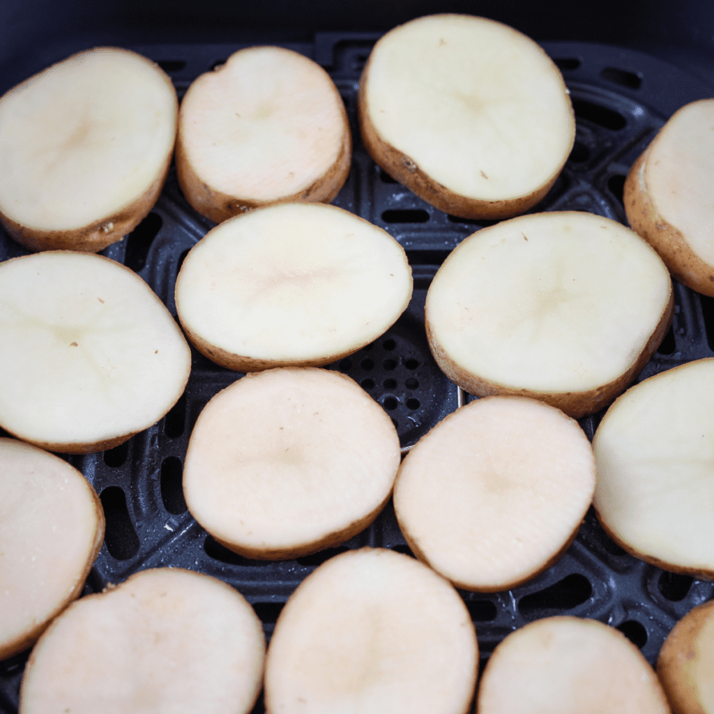"Step 2: Seasoning potato rounds with spices before cooking."