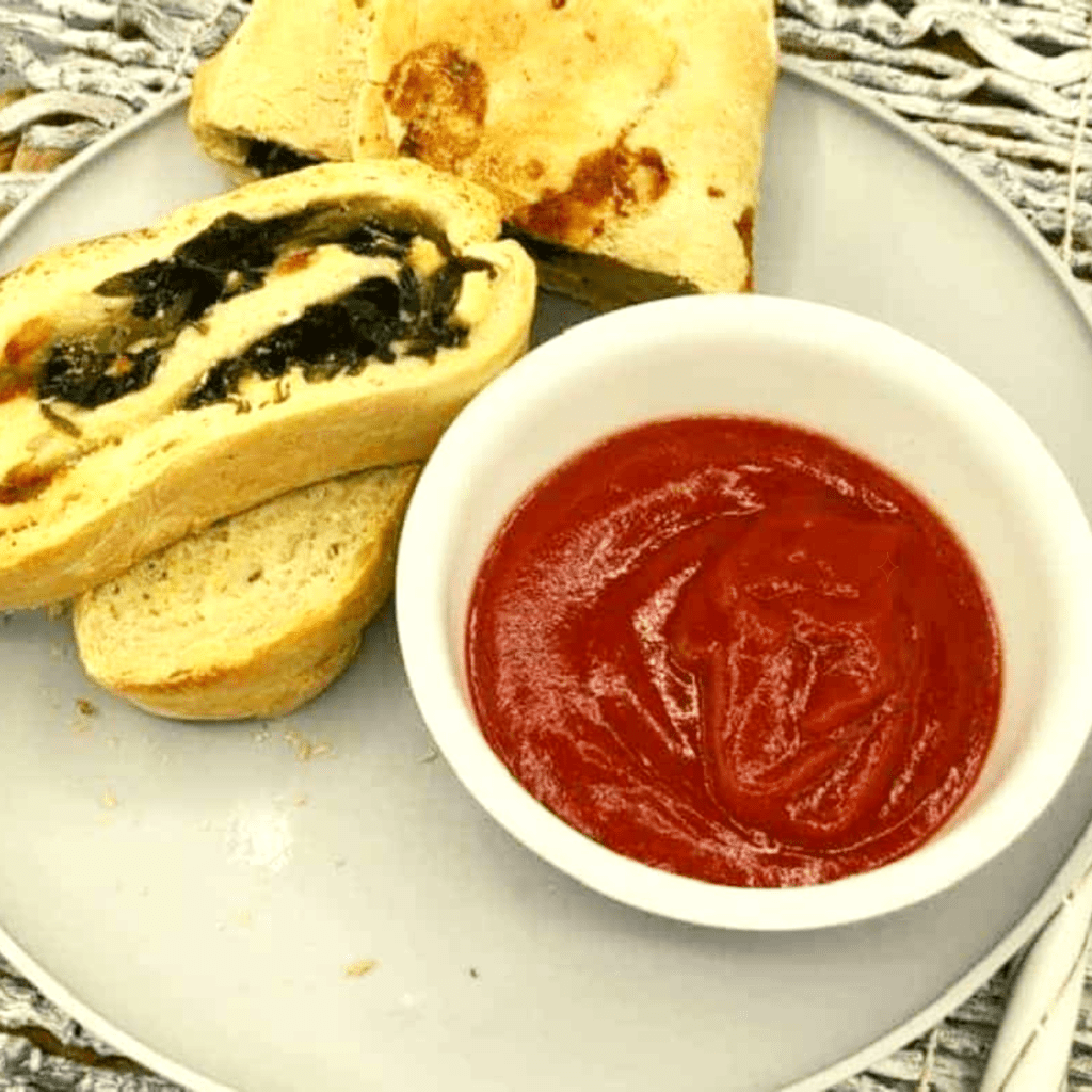 Air Fryer Spinach and Feta Stromboli sliced open, showing melted feta cheese and seasoned spinach inside.