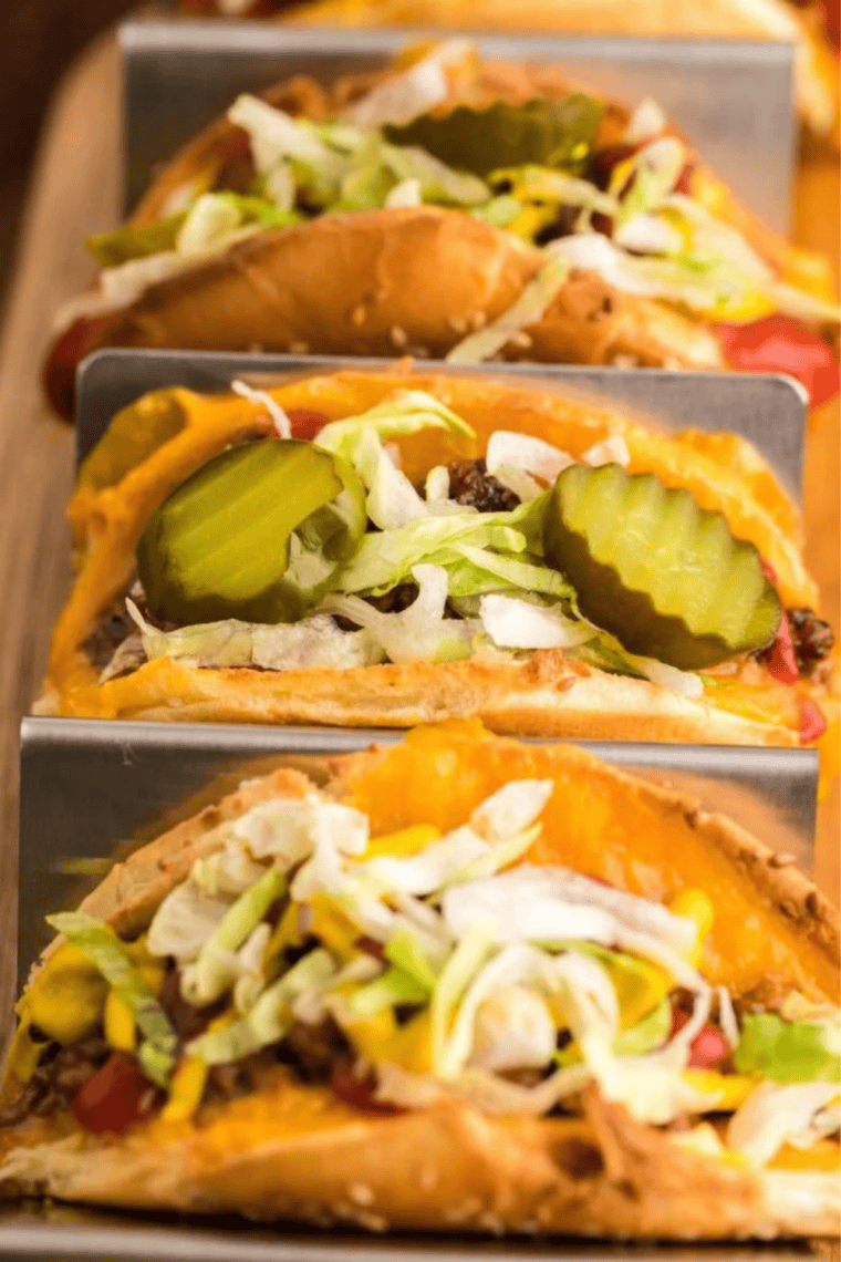 Air Fryer Taco Burgers topped with melted cheese, ground beef, shredded lettuce, and pickles, served fresh and ready to enjoy.