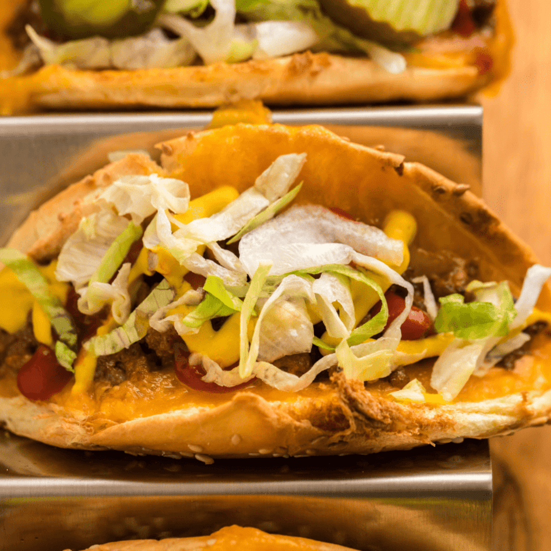 Juicy Air Fryer Taco Burger topped with melted cheese, fresh lettuce, tomatoes, and taco sauce, served on a toasted bun.