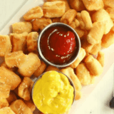 Copycat Culver's pretzel bites piled on a board with a cup of Wisconsin cheddar cheese sauce