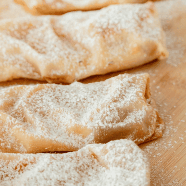Golden, crispy air fryer peach cobbler egg rolls with bubbling cinnamon-sugar peach filling