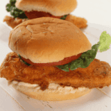 Golden fried chicken sandwich with lettuce and bun on a plate, homemade Jack in the Box style.