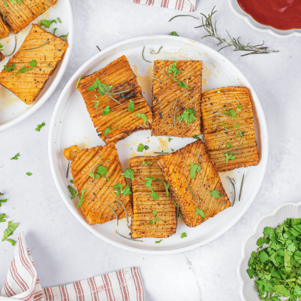 Air Fryer Accordion Potatoes on white plate with seasonings.