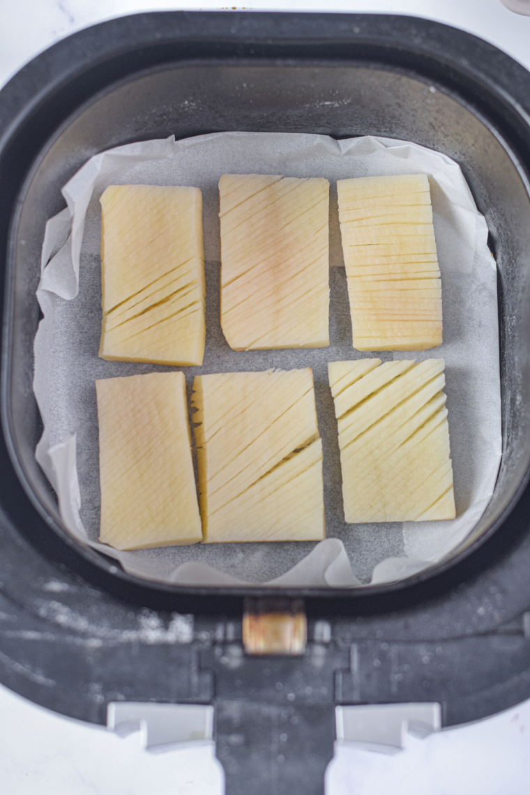 "Air fryer potatoes halfway through cooking, starting to crisp up."