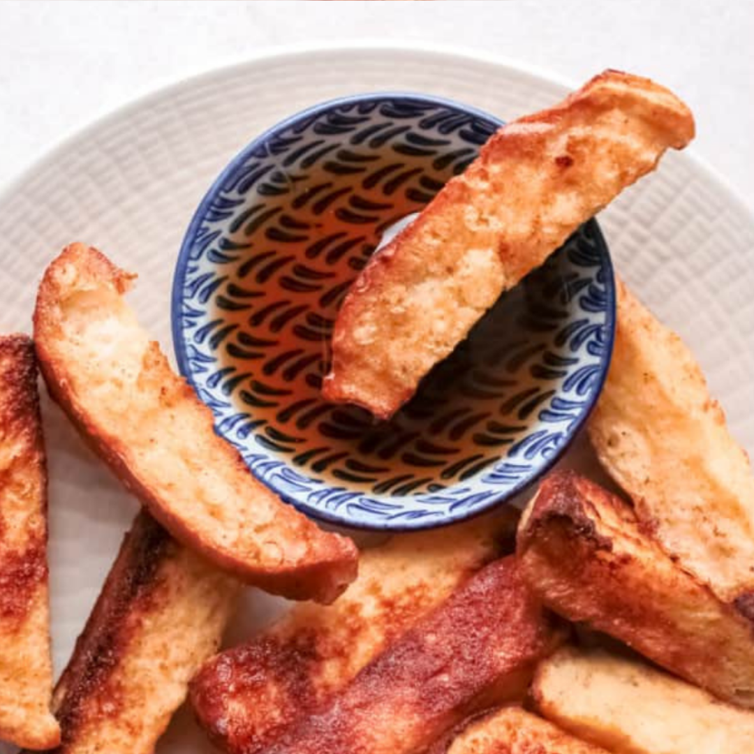 Crispy and golden Air Fryer Apple French Toast Sticks served with a side of syrup.