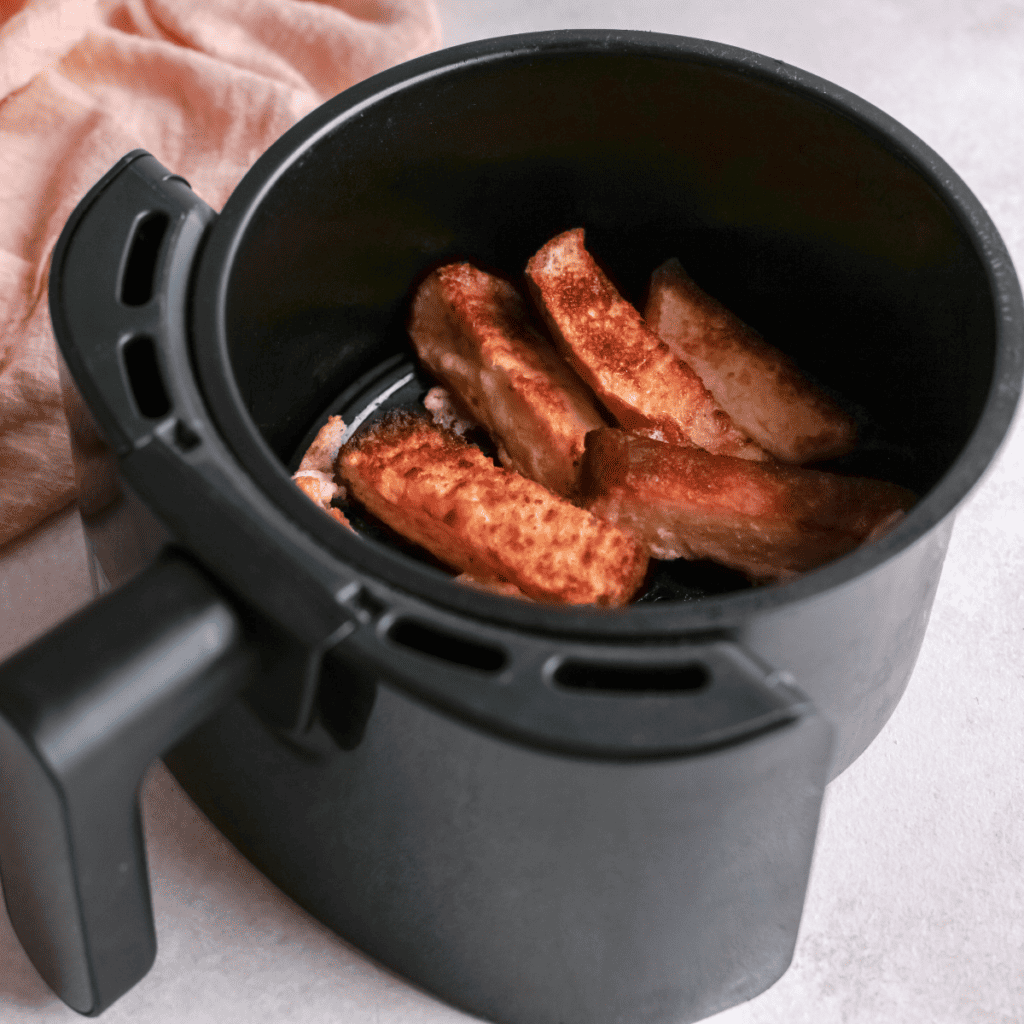Cooked Apple French Toast Sticks in the air fryer basket.