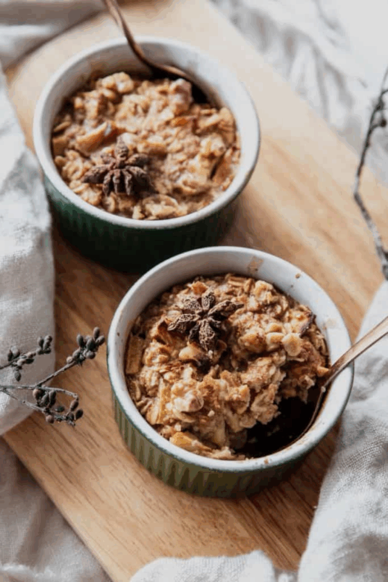 Golden-baked apple pie oatmeal in a bowl, topped with cinnamon and apple slices.