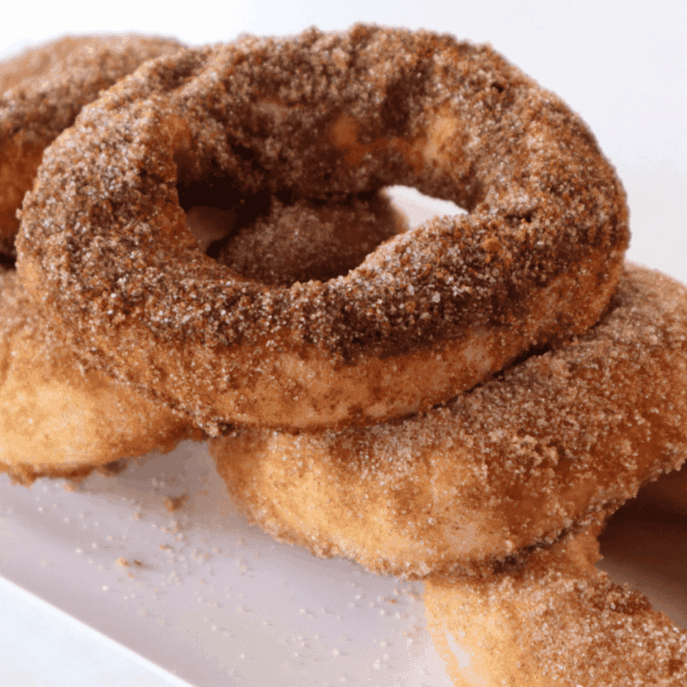 Golden air fryer donuts filled with gooey caramel, dusted with sugar and served on a plate.