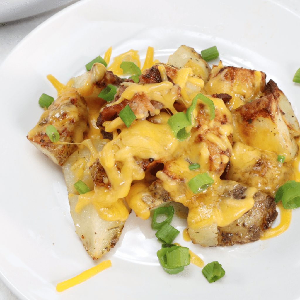 Crispy air fryer cheesy ranch potatoes topped with melted cheese and crispy bacon, served hot in a white bowl