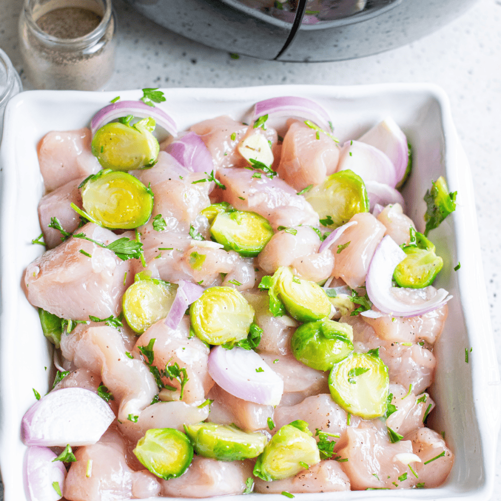 Cubed chicken breast being prepped on a cutting board after washing and drying, ready to cook in a preheated air fryer.