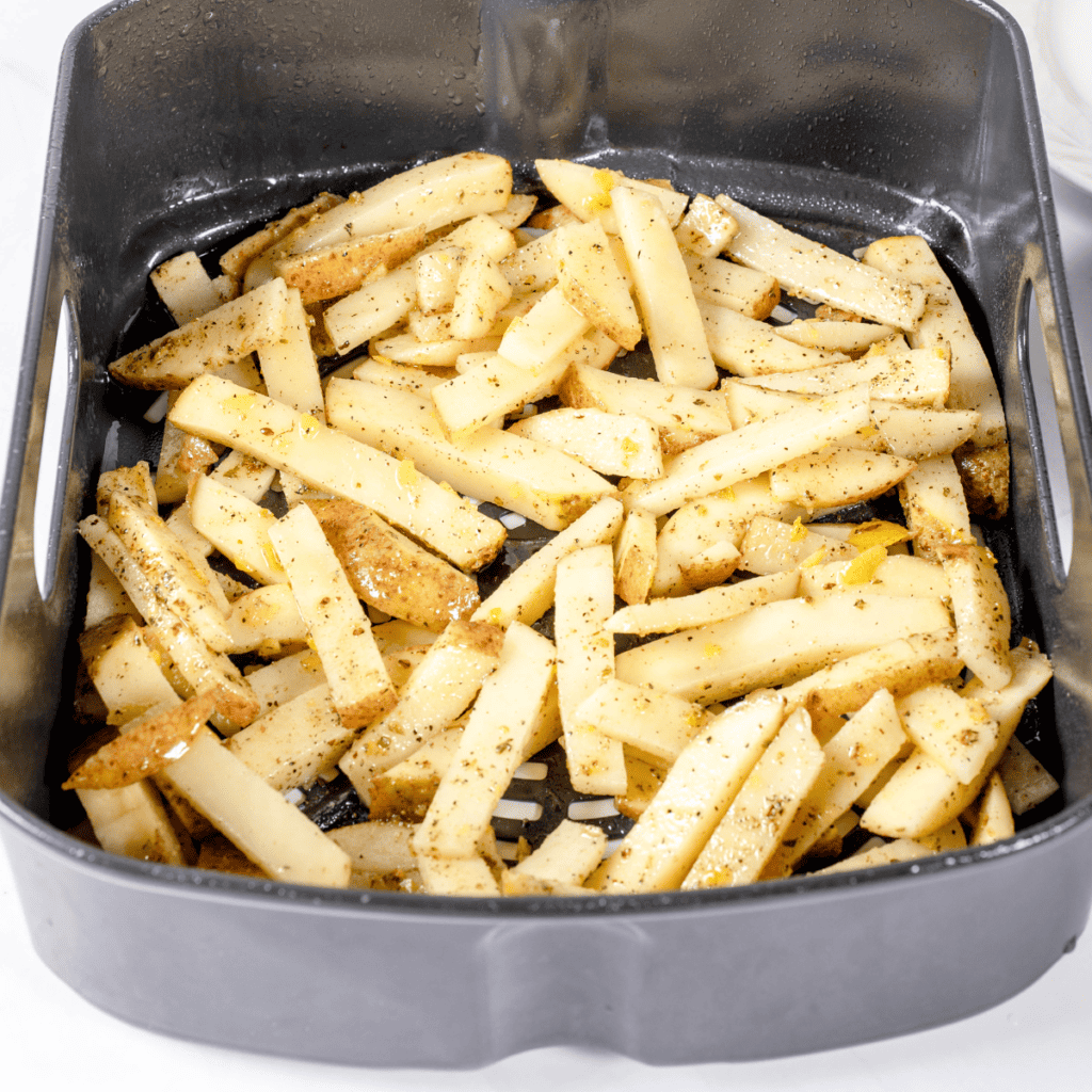Arrange seasoned fries in air fryer basket, cook at 400°F for 15-20 minutes, shaking halfway through for even crispiness.