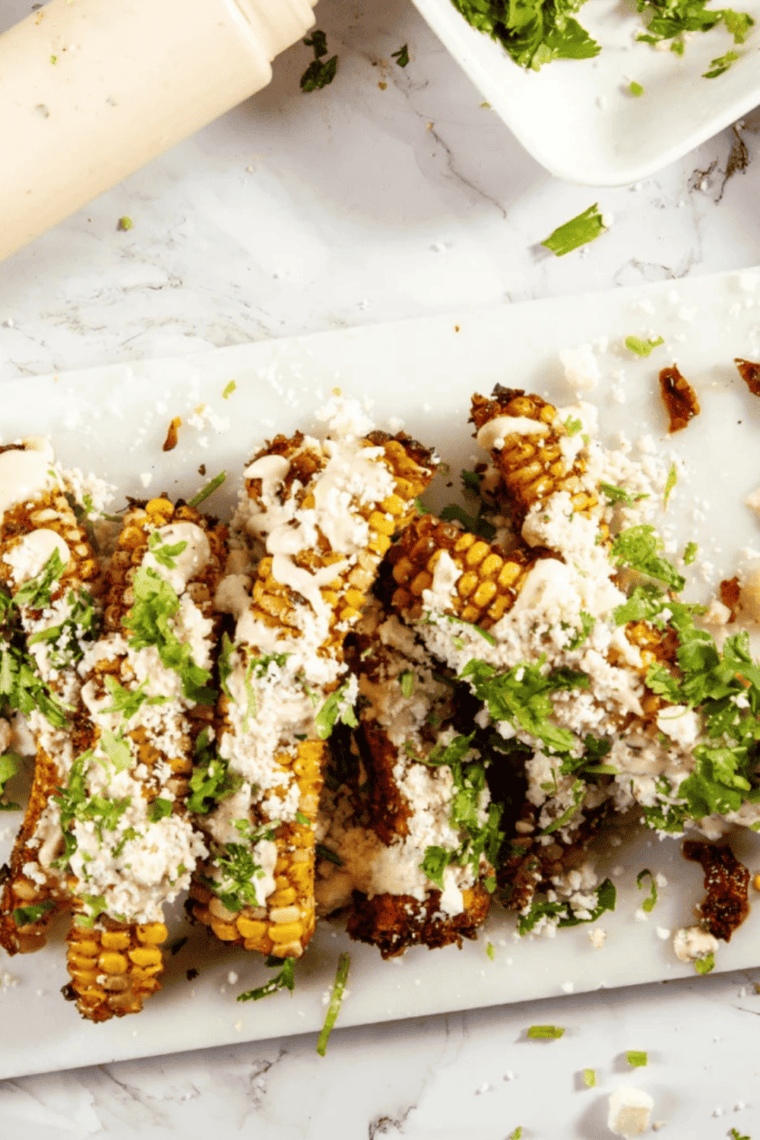 Crispy elote-style air fryer corn ribs drizzled with chipotle mayo and sprinkled with cotija and lime