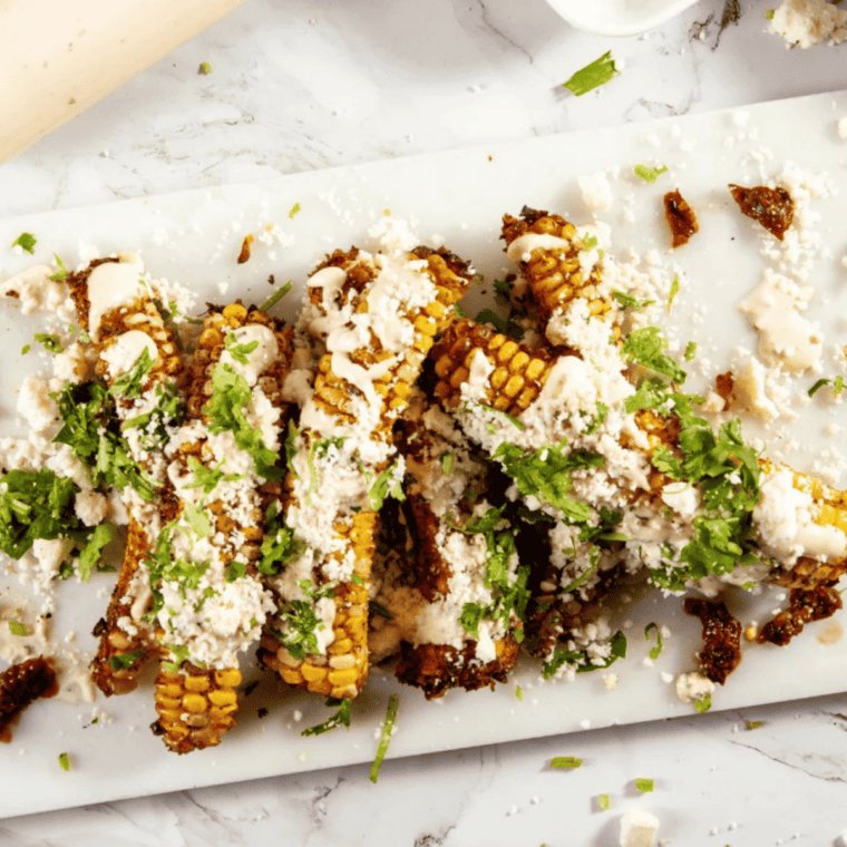 Plate of golden air fryer corn ribs garnished with cilantro and cotija cheese, elote style