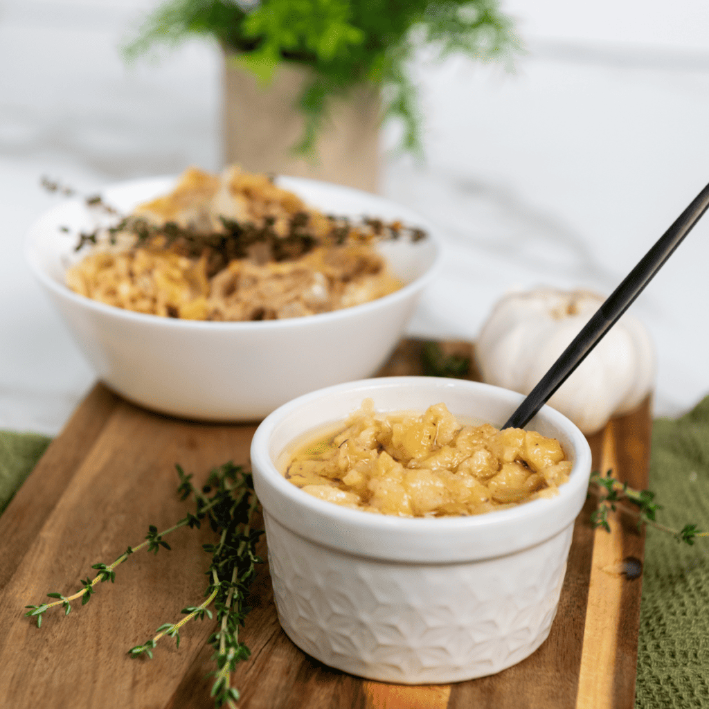 Golden, tender garlic cloves cooked in olive oil inside a small dish from the air fryer.
