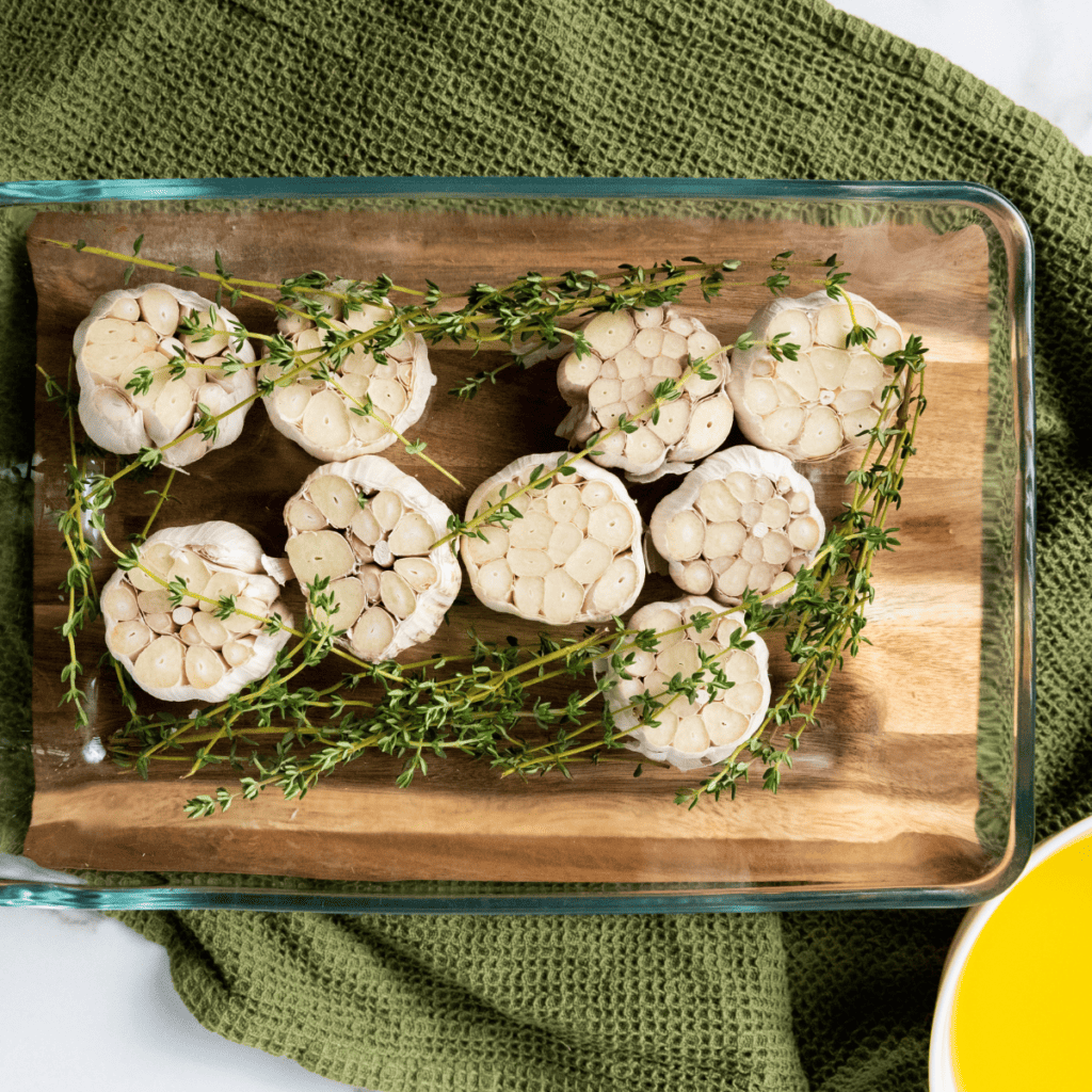 Garlic cloves arranged in a heatproof dish inside an air fryer, evenly spread in a single layer