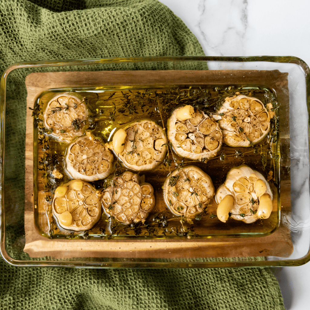 Garlic cloves submerged in olive oil inside a heatproof dish, ready for air frying.