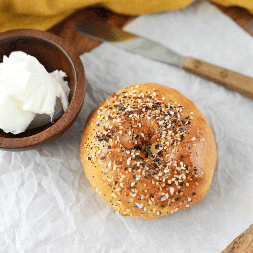 Air fryer gluten-free everything bagels stacked on a wooden board with crispy everything seasoning crust.