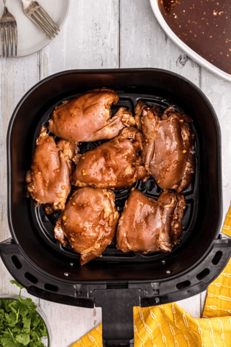 Chicken cooking in an air fryer, brushed with Huli Huli marinade for a juicy, flavorful finish.