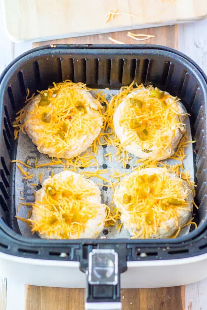 Shaping the dough into bagel forms and placing them on a parchment-lined air fryer basket.