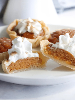 Air fryer pumpkin tarts topped with whipped cream on a white plate