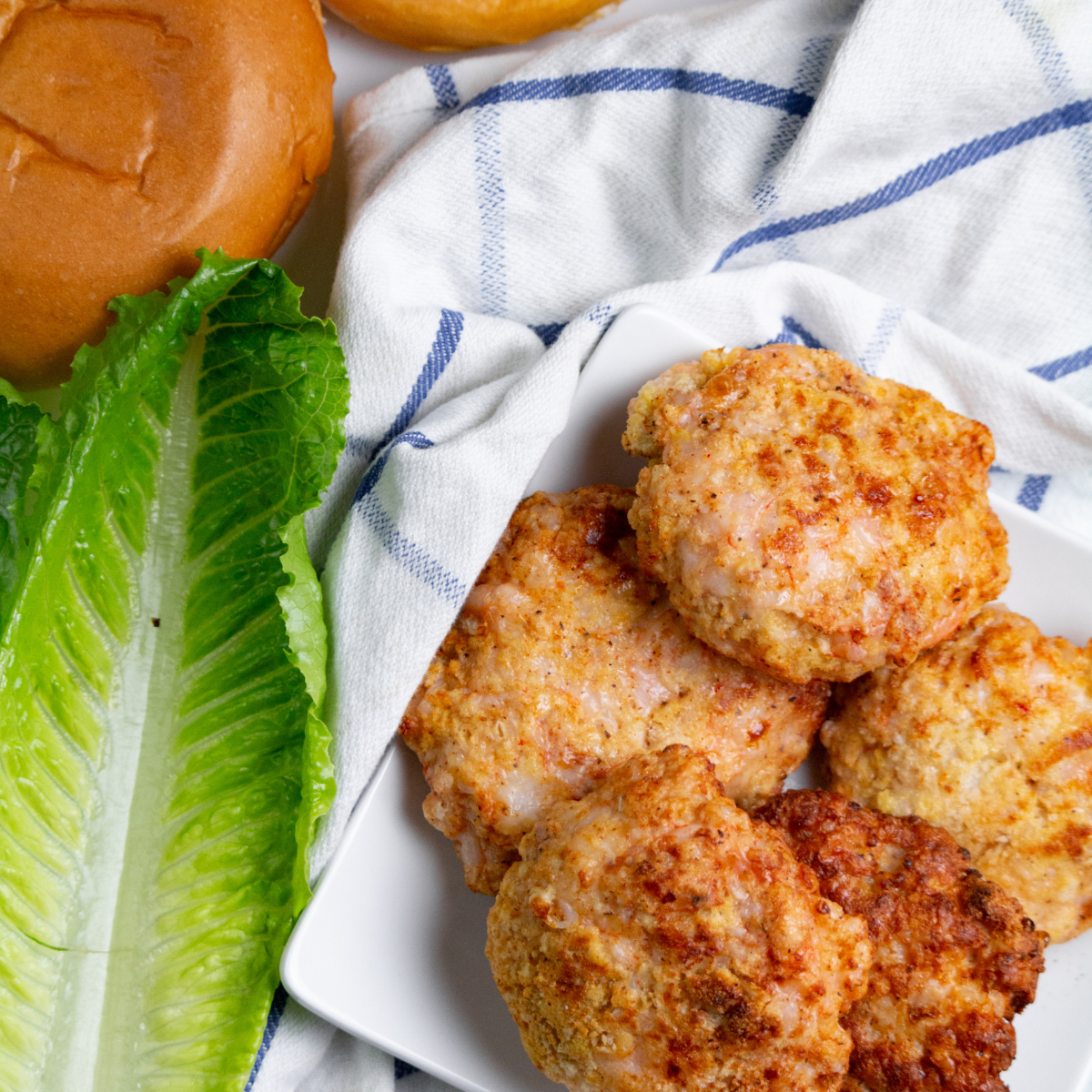 An air fryer shrimp burger loaded with fresh toppings like avocado and spicy sauce, served on a toasted bun.