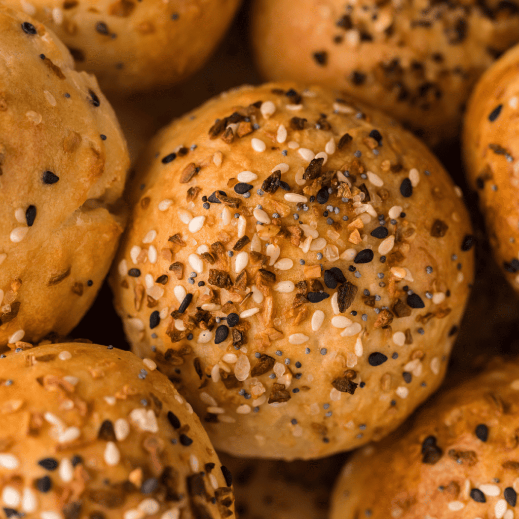 Viral TikTok 2-ingredient air fryer bagel bites split open to show the fluffy interior, topped with sesame and poppy seeds.