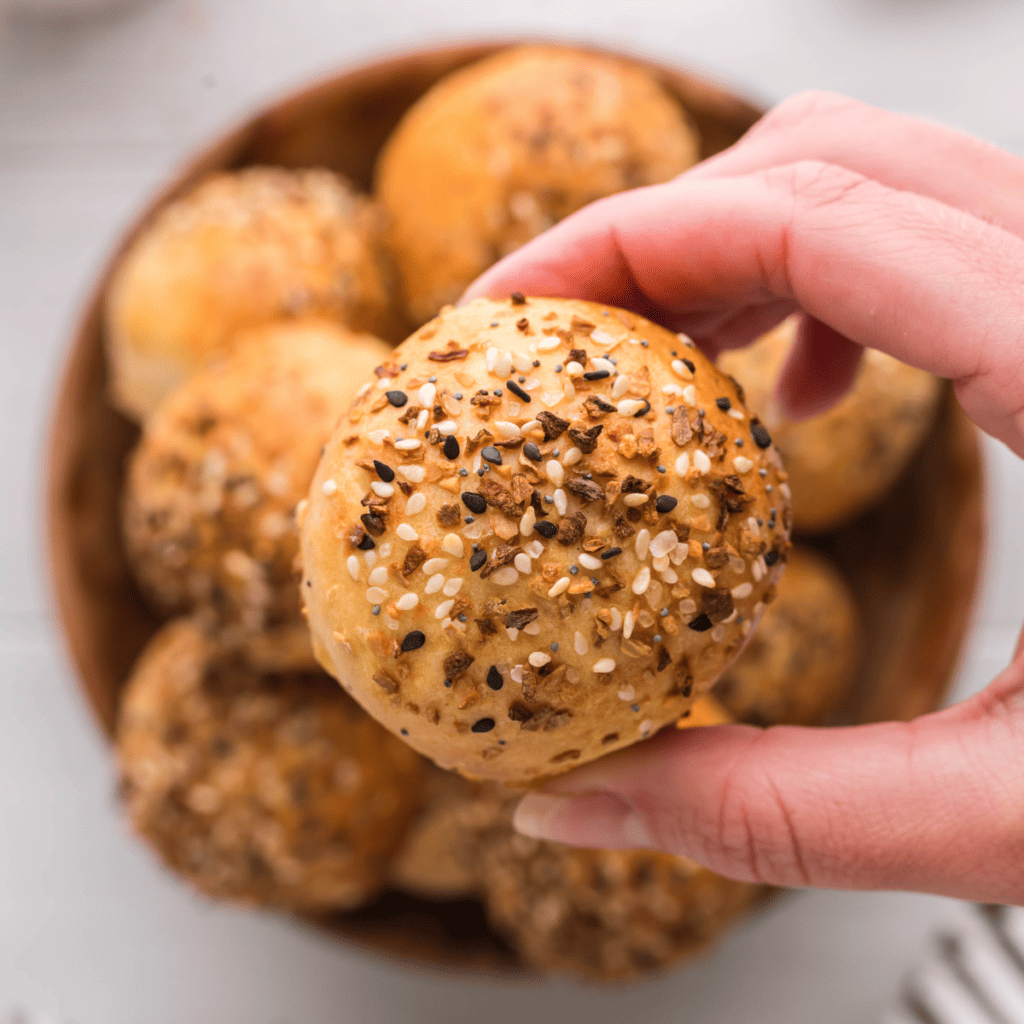 Stack of high-protein Greek yogurt bagel bites coated in everything seasoning, air fried until golden and arranged on parchment paper.