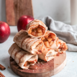 Crispy apple flautas on a white plate drizzled with salted caramel sauce
