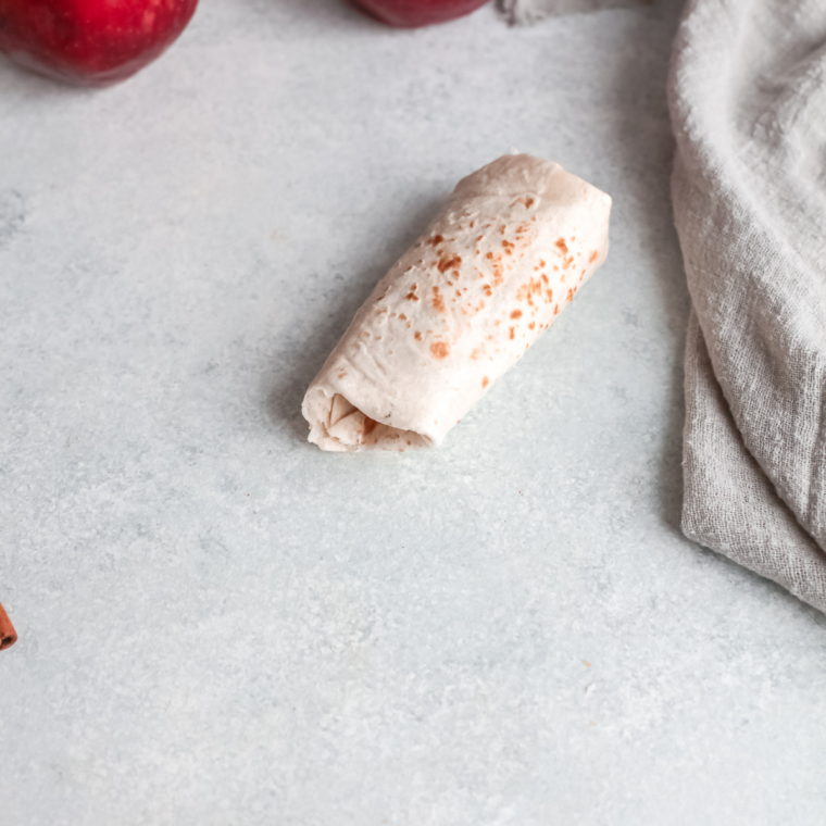 Rolled apple flautas arranged seam side down in an air fryer basket