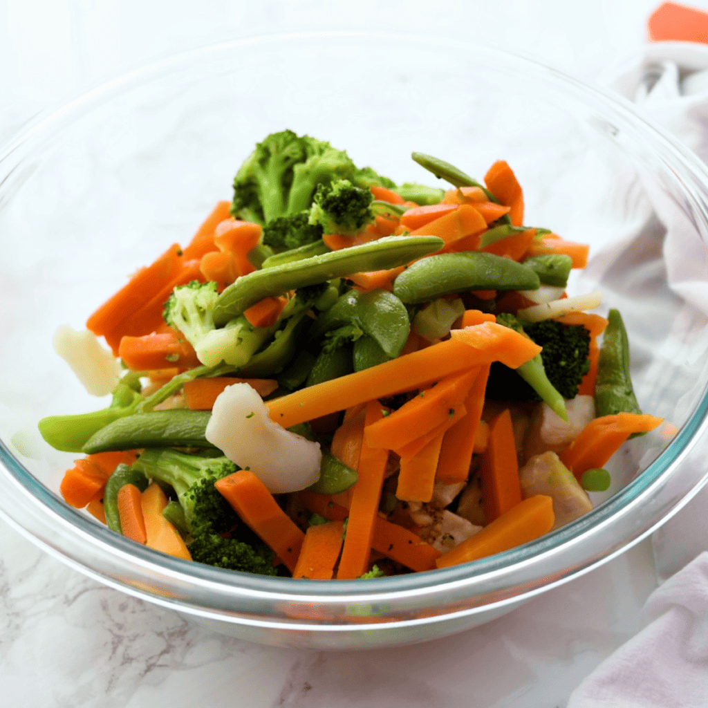 Chopped bell peppers, broccoli, and snow peas prepped in separate bowls