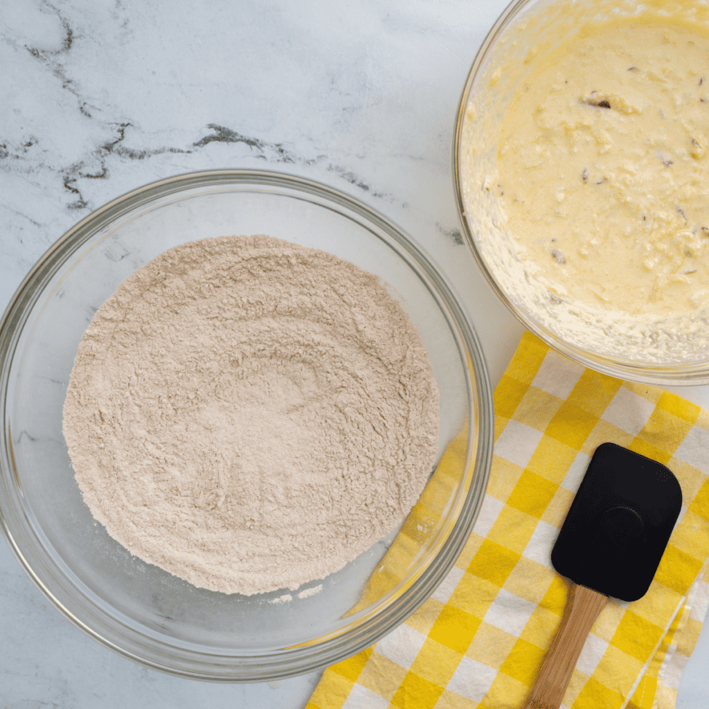 Mixing dry ingredients with wet ingredients until smooth batter forms for apple cider donuts.