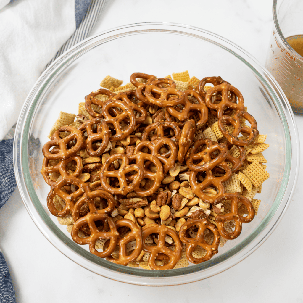 Chex cereal, pretzels, nuts, and crackers combined in a large mixing bowl