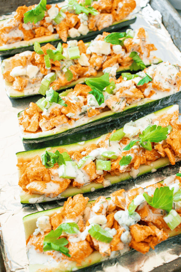 Drizzling ranch dressing over finished Buffalo Chicken Zucchini Boats for garnish.