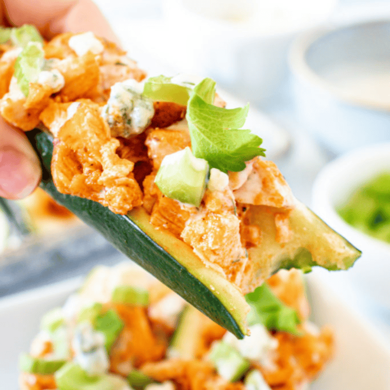 Baked Buffalo Chicken Zucchini Boats topped with melted cheese and ranch dressing.