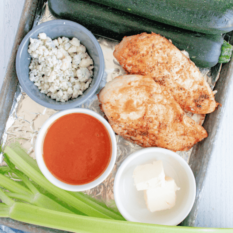 Close-up of a Buffalo Chicken Zucchini Boat filled with shredded chicken and garnished with green onions.